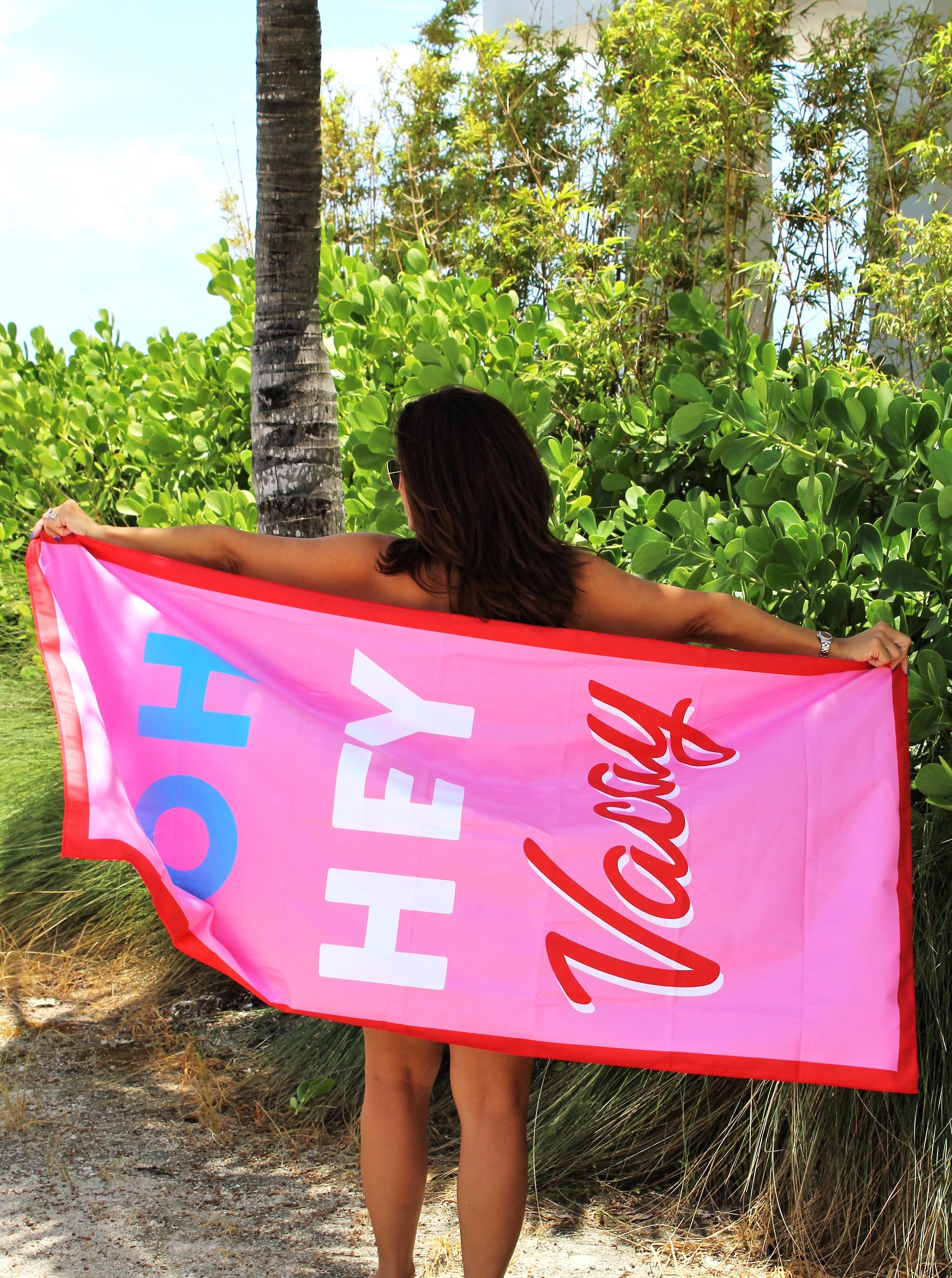 Woman standing showing a beach towel that says Oh Hey Vacay